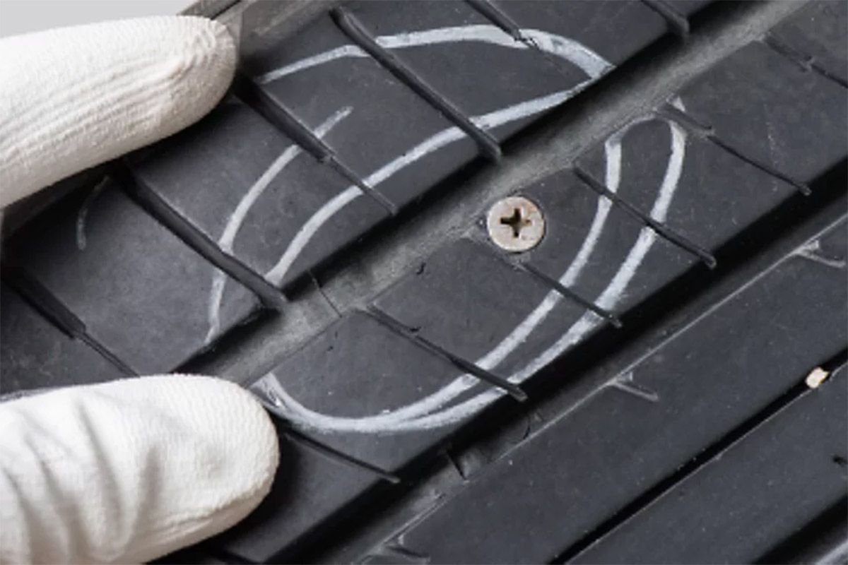 Hender som sjekker bildekk med verktøy